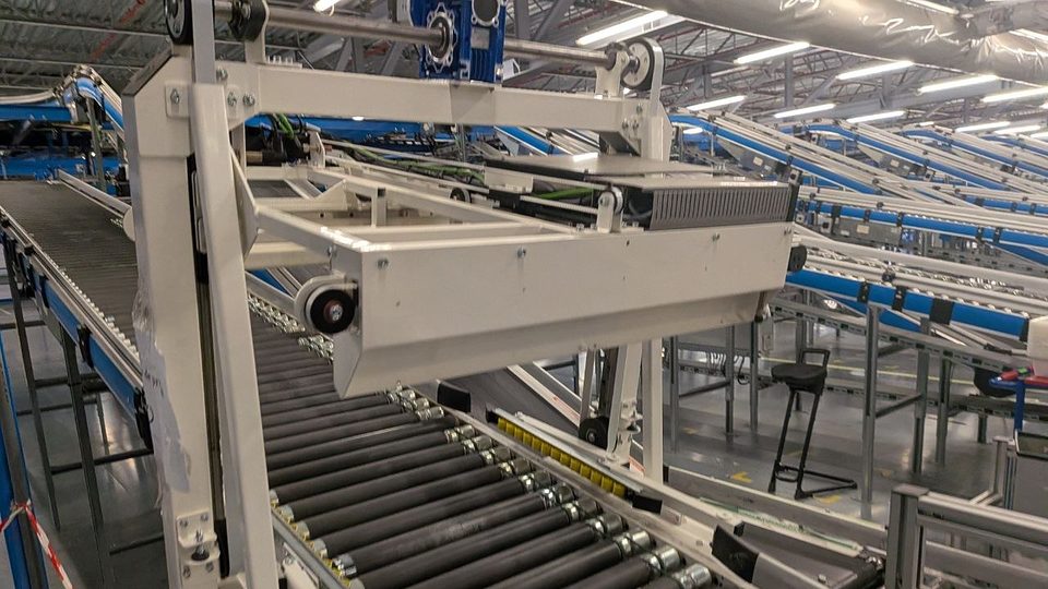 Cortadora automática de precintos instalada sobre un transportador de rodillos